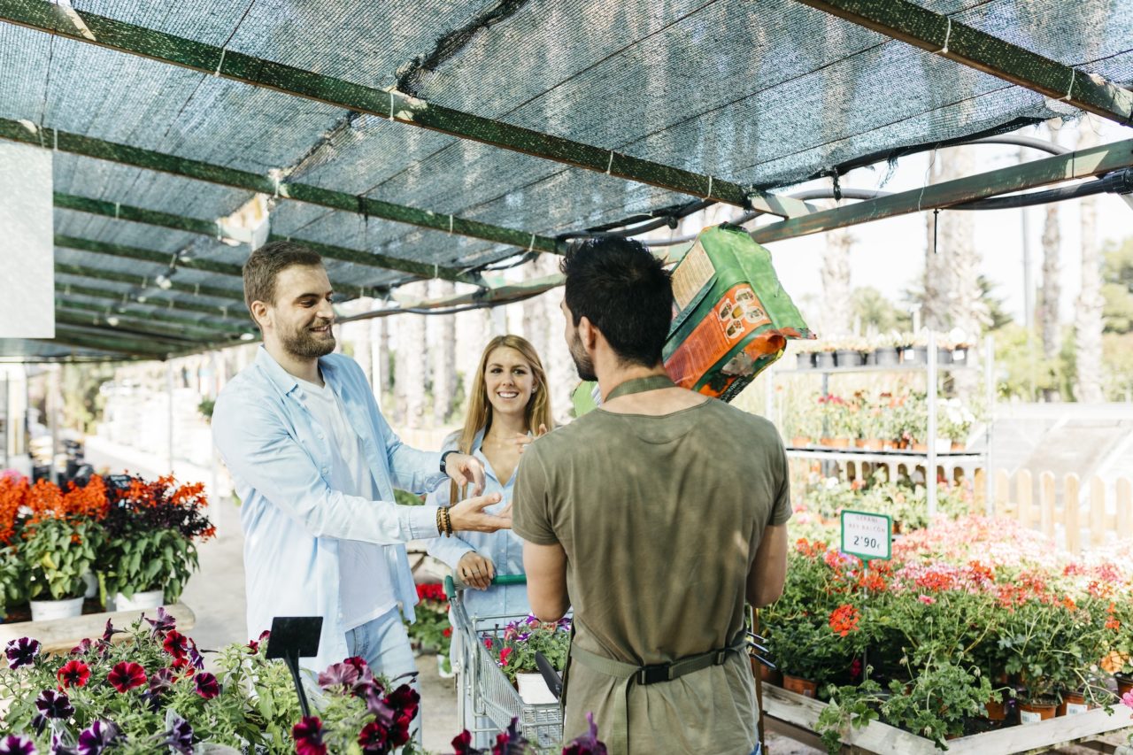 Worker in a garden center handing over soil to customers